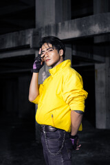 an Asian man with sleek black hair wearing a yellow jacket and jeans while posing