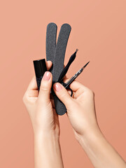 Female hands with nude  color nail polish holding manicure tools: a nail clipper, cuticle cutter and a nail file. a close-up demonstrating professional beauty service and manicure artist occupation.