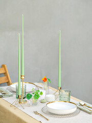 An elegant table arrangement for two. Sophisticated green candles and the combination of white and gold create a luxury setting for a special occasion, as a romantic date or a celebration dinner. 