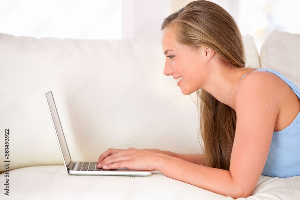 Canvas Prints Chatting with friends online. an attractive young woman using a laptop while lying on the sofa.