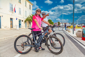 Active couple riding an E-Bike during vacations in the south