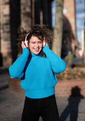 woman with headphones listening to music and dancing outdoors