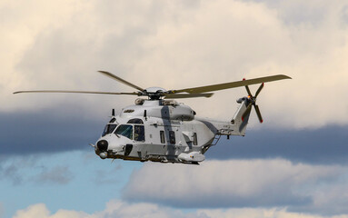 Civilian helicopter in the blue sky with gray white clouds.