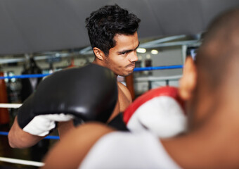 Fototapeta na wymiar Coming at you full force. two young boxers sparring in a ring.