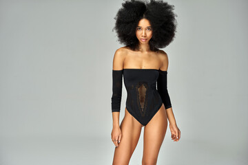 Beautiful african american girl with an afro hairstyle wear black bodysuit isolated on gray...