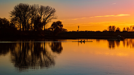 Sunset with reflections and rowers near Metten, Danube, Bavaria, Germany