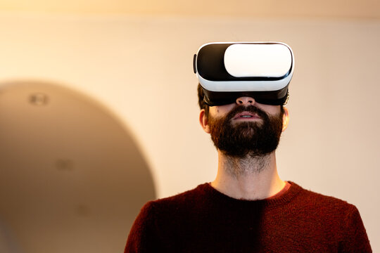 Amazed man wearing VR goggles against wall