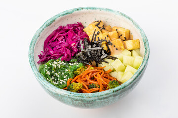 Bowl with tofu, carrots, broccoli, chuka, red cabbage, nori, white and black sesame seeds. Round green bowl on a white background. Close up 3/4