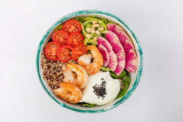 Poke bowl with shrimp, quinoa, poached egg, celery, cherry tomatoes, herbs, pine nuts and sesame seeds. Green round bowl on a white background. Top view.