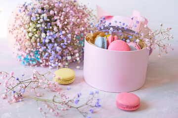 delicate bouquet with pink small flowers and a box of colorful macaroons
