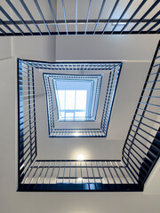 Bottom-up view of rectangular spiral staircase in modern multi-storey residential and office building