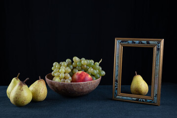 groupe de poires et coupe de fruits à côté d'un cadre entourant une poire sur fond noir