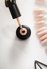 Gel lacquer standing at table. Close up view of black bottle standing at the white table, hand holding brush at the nail salon, color samples. Beauty routine concept. Top view