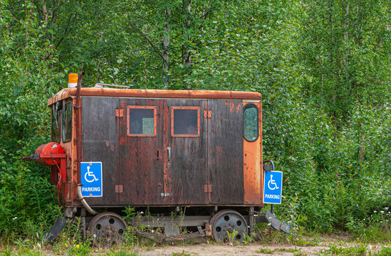 Fox, Alaska, USA - July 26, 2011: Eldorado Gold Mine museum and park. Used abandoned and rustig small workers wagon to enter in placer mining operation. Backed by green trees