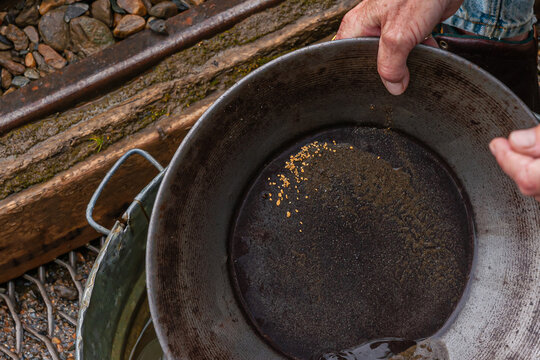 Fox, Alaska, USA - July 26, 2011: Eldorado Gold Mine museum and park. Hand shows pan with gold dust particles left over after swirling and washing