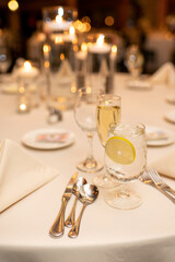 Close up of Lemon Water and Modern Dinner Table Setting at Event with Lights and Candles, Dinner Party Concept