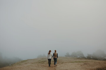 Lesbian couple walking into fog - Powered by Adobe