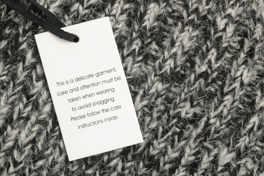 Close up of luxury clothing hang tag. Delicate garment swing tag. Laundry care washing instructions clothes label. 