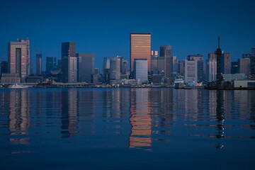 Fototapeta na wymiar First rays of sun in Tokyo. Reflection of the sunrise in glass skyscraper office buildings in Tokyo, beautiful night landscape during the blue hour of this modern city in Japan.