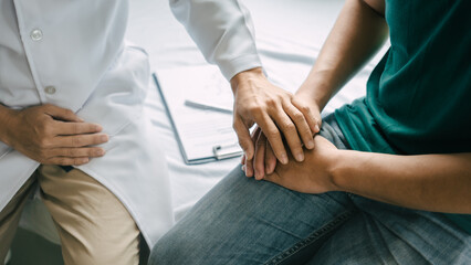 Male patient consulting a medical specialist at hospital. encouragement by holding hands