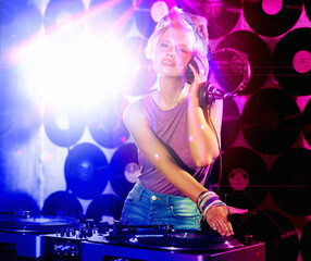 No one can beat her tunes. a hip young DJ holding her headset looking at the camera.
