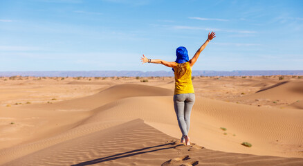 Woman tourist walking on sand dune in Sahara desert