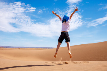 Children jumping in sand dunes in the Sahara desert