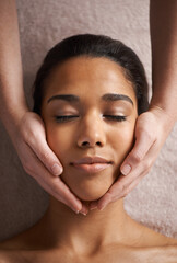 Massaging the body and mind. a beautiful young woman getting a head massage at a spa.