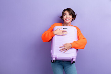 Photo of positive lovely lady trendy clothes hold baggage look empty space dream weekend trip abroad isolated on purple color background