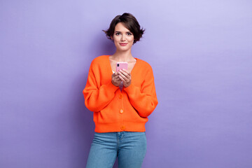 Photo of pretty cute lady dressed orange cardigan communicating modern device isolated purple color background