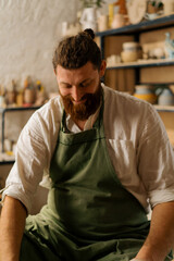 Fototapeta premium Pottery workshop satisfied and smiling bearded potter at work