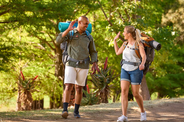 Couple With Backpacks Giving Each Other High Five On Vacation Hiking Through Countryside Together