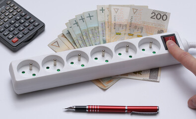 Fototapeta Listwa przedłużacza podłączonego do prądu leżąca na banknotach obok kalkulatora i długopisu obraz