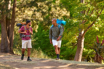 Two Male Friends With Backpacks On Vacation Hiking Through Countryside Together