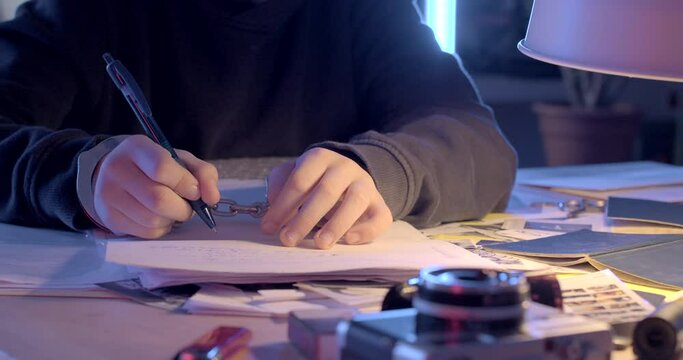 The handcuff shakes hands. Teenager's hand writes text on paper handcuffed hand. Detention and signing of documents in conditions of detention.