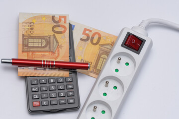 Listwa przedłużacza podłączonego do prądu obok kalkulatora i banknotów euro - obrazy, fototapety, plakaty