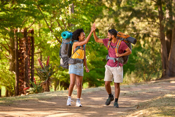 Couple With Backpacks Giving Each Other High Five On Vacation Hiking Through Countryside Together