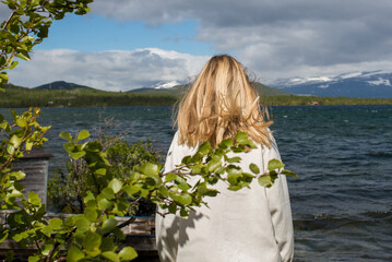 Fototapeta premium Young woman enjoy the beautiful natural scenery in the north. Lake and mountains. Tourist attraction in Norway. Amazing scenic outdoor view. Travel, adventure, relaxed lifestyle. Lofoten Islands