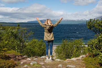 Young woman enjoy the beautiful natural scenery in the north. Lake and mountains. Tourist attraction in Norway. Amazing scenic outdoor view. Travel, adventure, relaxed lifestyle. Lofoten Islands