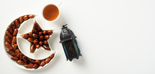 Ramadan Kareem background with Arabic lantern, dried dates in Islamic star and crescent plate, cup of tea. Muslim holiday Ramadan banner design.