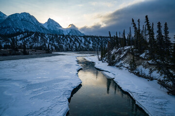 frozen siffleur mountain river during sunrise with refelction and pieces of ice in water