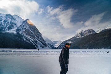 man ice skating on  frozen lake luise during winter with mountains on background