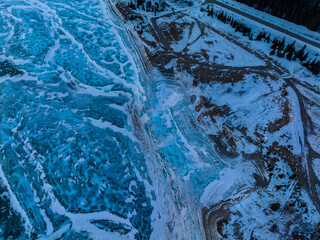 aerial view of blue ice on bank of frozen abraham lake 