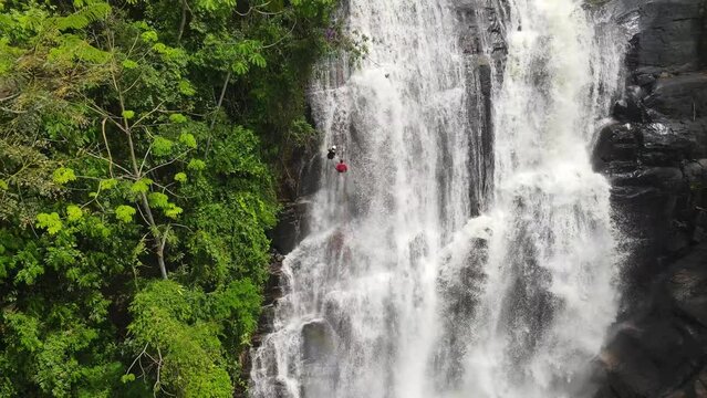 Woman abseiling a waterfall in the heart of the forest