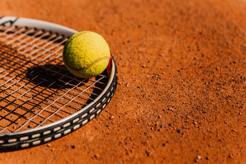 Light orange empty outdoor clay court surface dry grungy ground baseline detail for playing tennis with net in sunny day with racket yellow green ball, gravel texture background, copy space for text 
 - obrazy, fototapety, plakaty