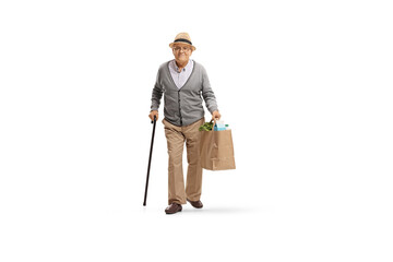 Full length portrait of an elderly man with a cane walking and carrying a paper grocery bag