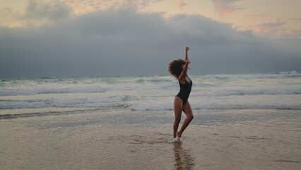 Girl making wheel beach sand gloomy evening. Woman performing acrobatic element.