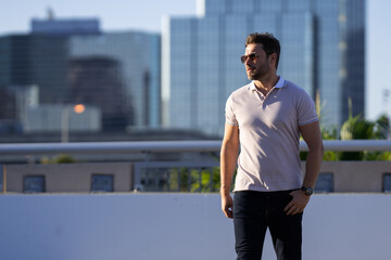 Portrait of handsome confident man in city. Portrait of confident man in modern big american city. Stylish lambersexual model. Sexy man dressed in polo. Fashion male posing on street in Tampa.