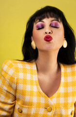 Studio portrait of a caucasian woman wearing an 80s fashionable yellow blazer and red lipstick. The...