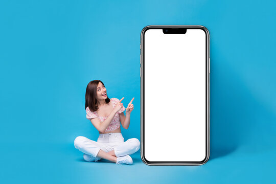 Photo of cute stylish lady sit look hand demonstrate recommend use buy telephone empty space promo isolated on blue color background